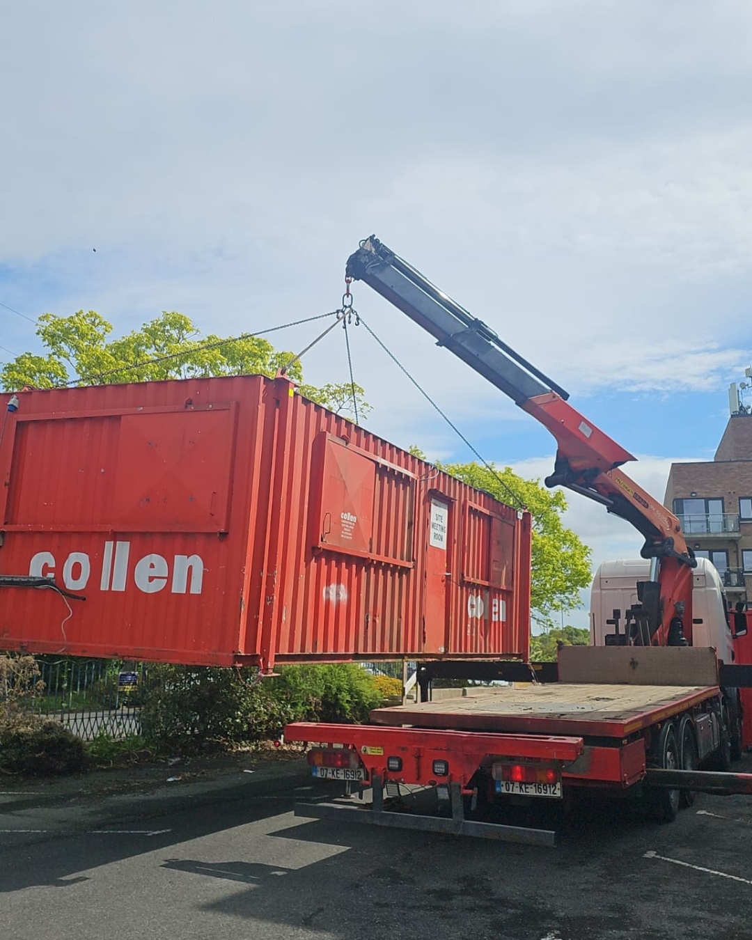 HIAB crane lifting a shipping container onto a flatbed truck in Ireland